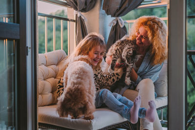 Happy child with smile plays on summer at home with mom, dog at sunset. cat, dog, pets family member