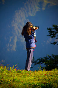 Side view of girl photographing on field