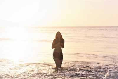 Happy young woman girl enjoying the ocean having fun at the beach under sky during sunrise or sunset