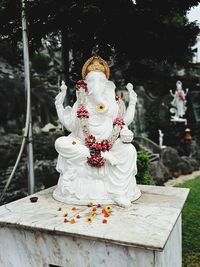 Sculpture of buddha statue against trees