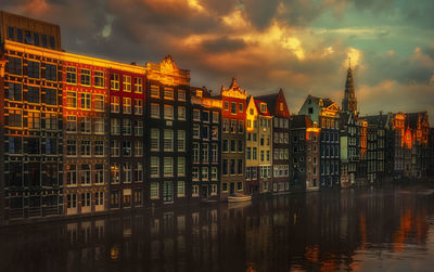 Reflection of buildings in canal against sky at dusk