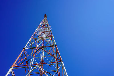 Low angle view of communications tower against clear blue sky