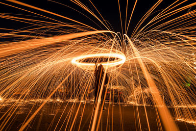 Silhouette man spinning wire wool on field at night