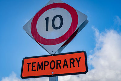 Low angle view of road sign against sky