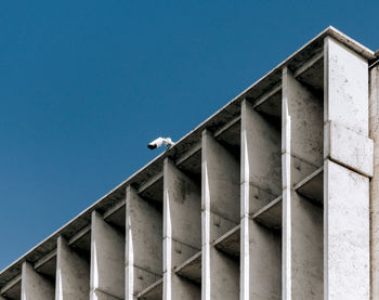 Surveillance camera on top of concrete building, blue sky, minimalist, minimalism, architecture.