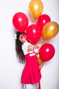 Full length of woman holding balloons against white background