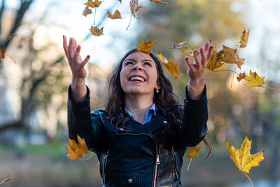 Young woman smiling with leaves in autumn