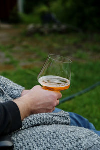 Low section of man holding wineglass outdoors 