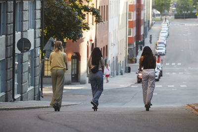 Young female friends riding electric push scooters in city