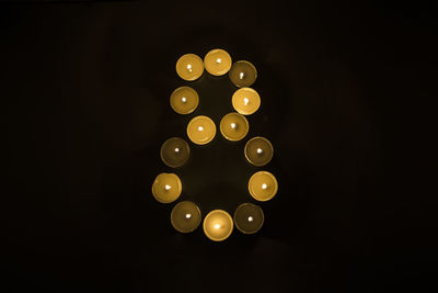 Directly above shot of illuminated tea light candles on black background