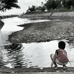 Rear view of woman sitting on shore