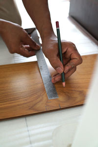 Cropped image of person drawing on wood