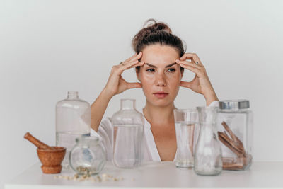 Portrait of a young girl with transparent vessels on a white table