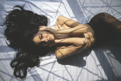 High angle portrait of woman lying down on bed