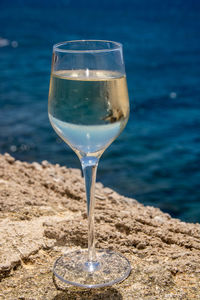 Close-up of wineglass on beach