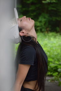 Young woman with eyes closed leaning on wall