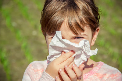 Close-up of girl blowing nose