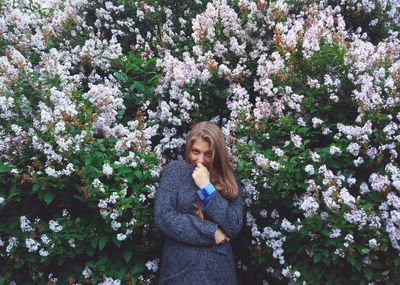 Portrait of young woman standing against plants