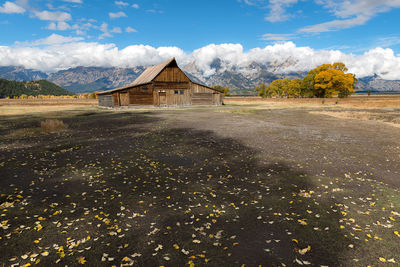 Built structure on field by mountain against sky