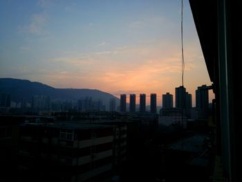 Silhouette buildings in city against sky during sunset