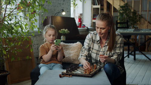 Mother and daughter playing chess at home