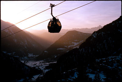 Overhead cable cars over snowcapped mountains against sky