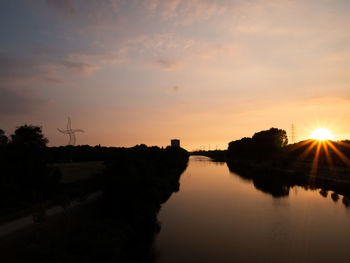 Scenic view of canal against sky during sunset