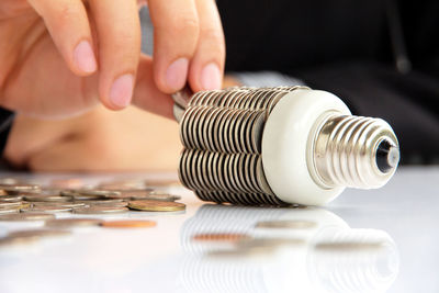 Midsection of man with light bulb and coins at table