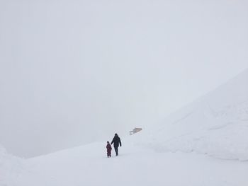 People on snowcapped mountain against sky