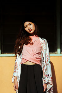 Beautiful young woman standing against wall