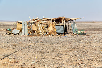 Damaged hut on beach against clear sky