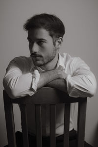 Portrait of young man looking away against wall