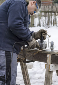 Worker cutting metal with grinder on table during winter