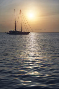 Silhouette sailboats on sea against sky during sunset