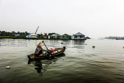 Man rowing boat in water against sky