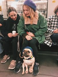 Women sitting in subway train with pug