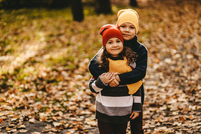 Happy cheerful children in warm clothes have fun walking running in autumn park playing with leaves