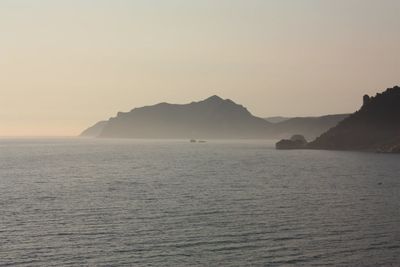 Scenic view of sea and mountains against sky