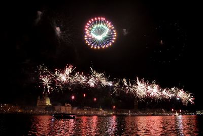 Firework display over river against sky