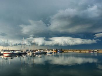 Boats in marina at harbor against storm clouds