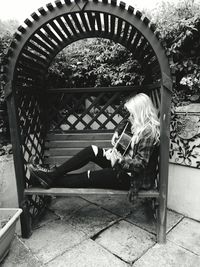 Teenage girl playing guitar on bench