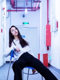 Portrait of young woman sitting on chair indoors