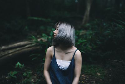 Rear view of young woman standing in forest