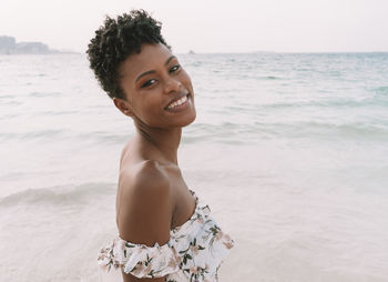 Portrait of smiling young woman standing on beach