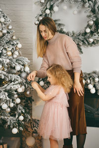 Young woman standing by christmas tree