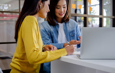 Young woman using mobile phone in laptop