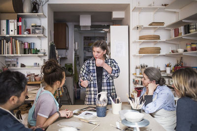 Mature female potter giving presentation during meeting at workshop