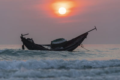 Fishing boat in sea against sky during sunset