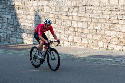 Man riding bicycle on road against wall