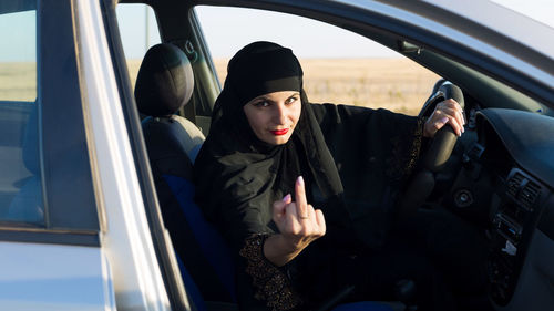 Portrait of woman in hijab gesturing while sitting in car